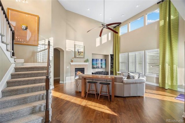 1133 Lucky Ct, Castle Rock, CO 80109 - living room with a lit fireplace, wood finished floors, a towering ceiling, stairs, and ceiling fan