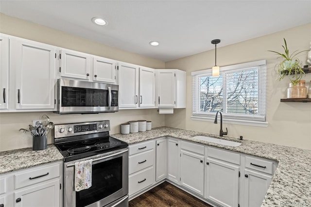 kitchen featuring dark wood-style floors, appliances with stainless steel finishes, light stone countertops, white cabinetry, and a sink