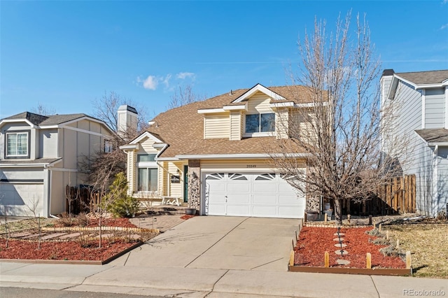 traditional-style home with driveway, an attached garage, and a shingled roof