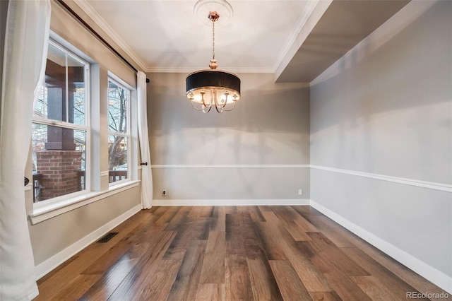 unfurnished dining area with dark hardwood / wood-style flooring, crown molding, and a chandelier