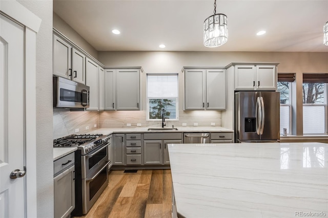 kitchen featuring sink, gray cabinetry, hanging light fixtures, stainless steel appliances, and dark wood-type flooring