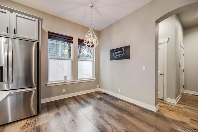 unfurnished dining area with dark wood-type flooring and an inviting chandelier