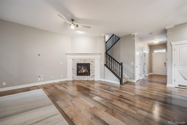 unfurnished living room with ceiling fan, wood-type flooring, and a fireplace