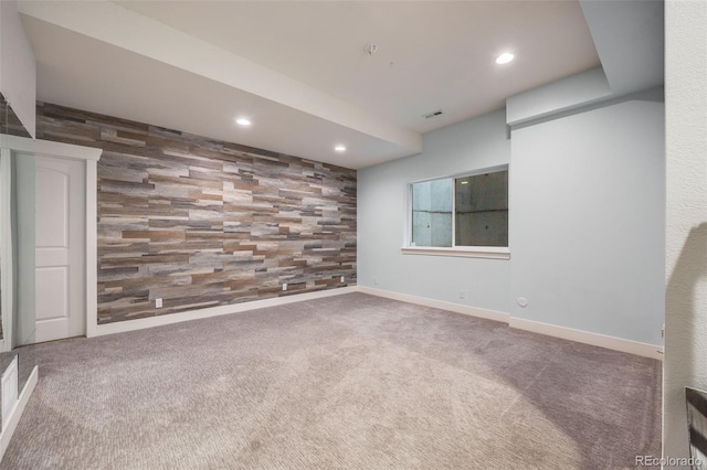 carpeted spare room with wood walls