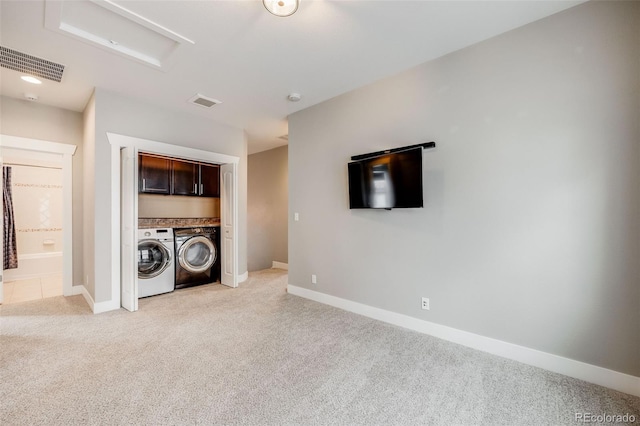 laundry area featuring cabinets, separate washer and dryer, and light carpet