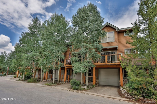 129 Logger Ln, Winter Park, CO 80482 - view of front of home with a garage, stone siding, driveway, and a balcony