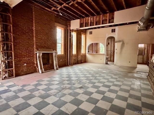 2801 Champa St, Denver, CO 80205 - unfurnished living room featuring brick wall, a towering ceiling, and arched walkways
