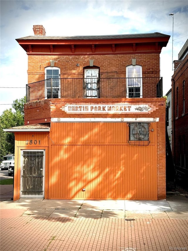 2801 Champa St, Denver, CO 80205 - view of front facade featuring brick siding, a chimney, and a balcony
