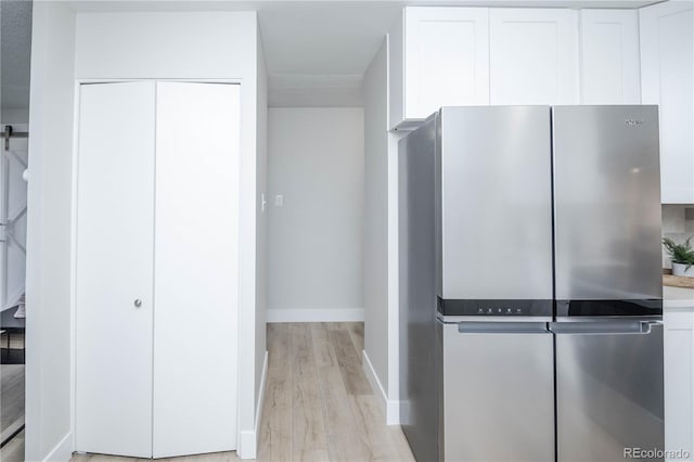 kitchen with light hardwood / wood-style floors, stainless steel fridge, and white cabinetry