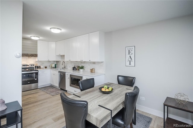 dining space featuring light wood-type flooring and sink