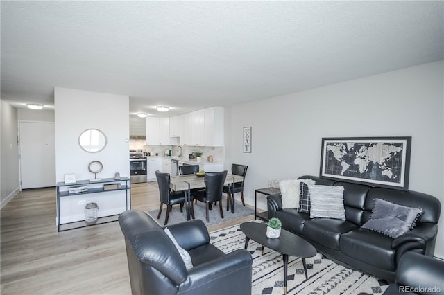 living room featuring a textured ceiling, light hardwood / wood-style flooring, and sink