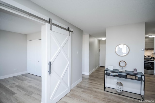 hall with a barn door and light hardwood / wood-style flooring