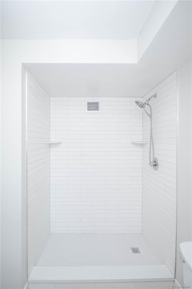 bathroom with a tile shower and toilet