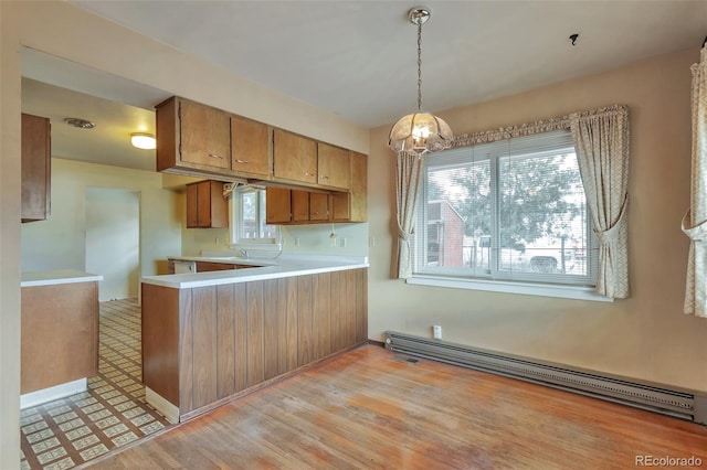 kitchen featuring kitchen peninsula, light hardwood / wood-style flooring, a healthy amount of sunlight, and a baseboard heating unit