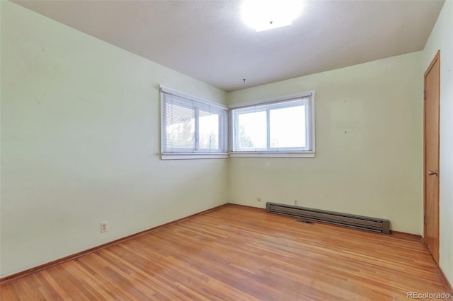 empty room featuring light wood-type flooring and a baseboard heating unit