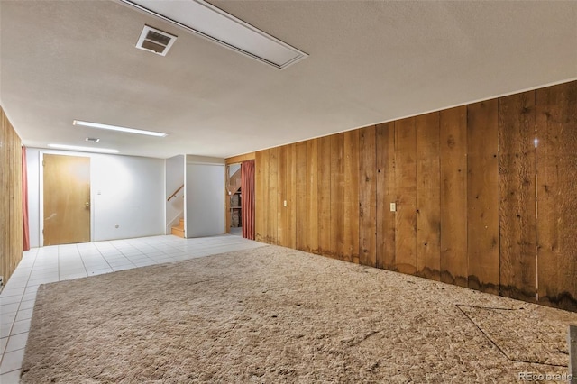 empty room featuring light tile patterned floors, a textured ceiling, and wood walls