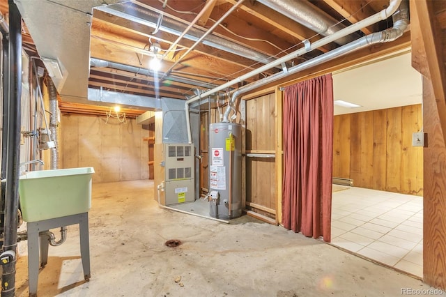 basement with heating unit, wood walls, sink, and gas water heater