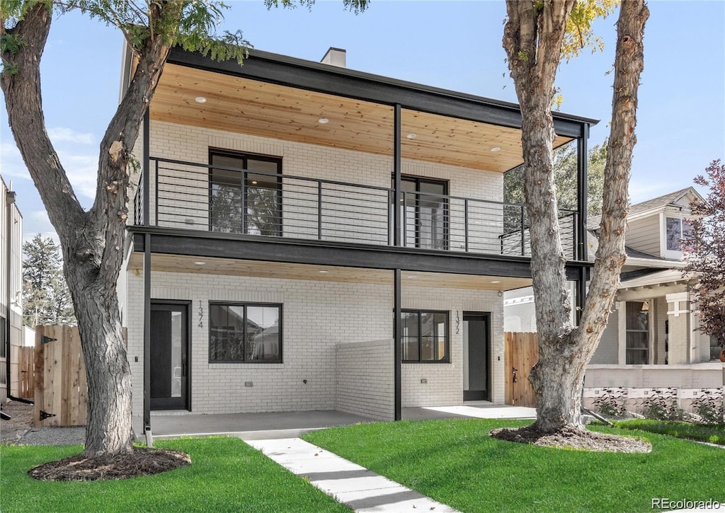 contemporary house featuring a patio, a balcony, and a front lawn