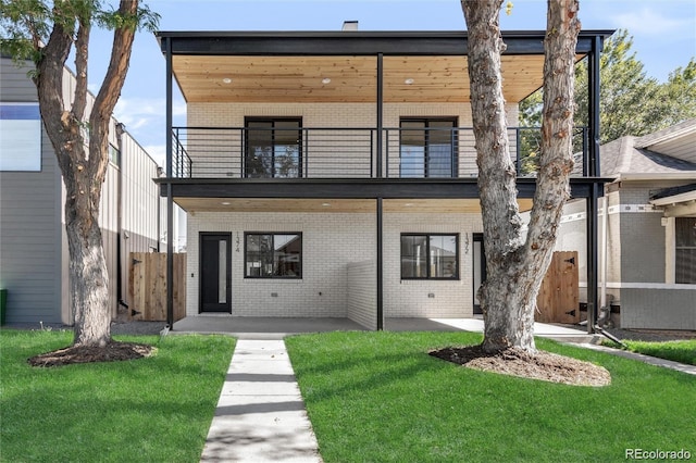 modern home with a balcony, a front lawn, and a patio area