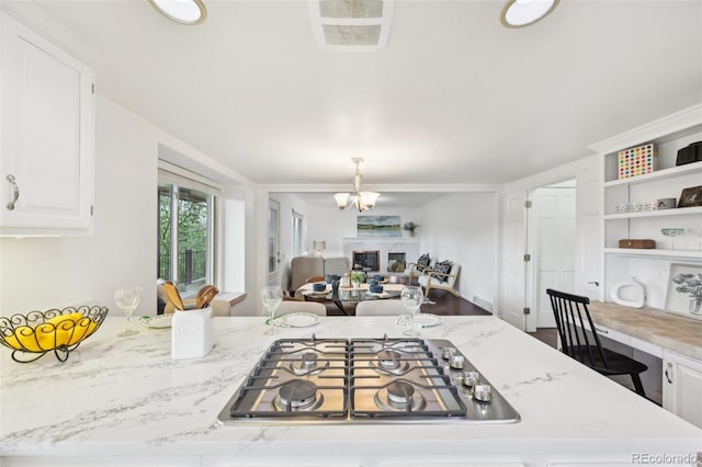 8424 E Otero Cir, Centennial, CO 80112 - kitchen with stainless steel gas cooktop, white cabinets, a chandelier, open floor plan, and decorative light fixtures