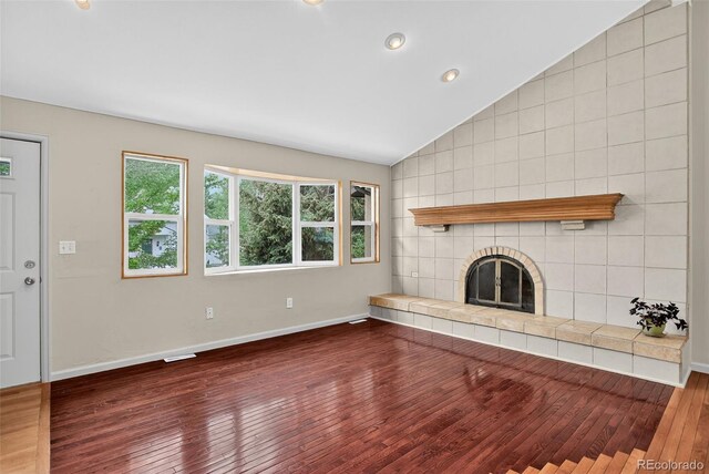 18445 W 59th Dr, Golden, CO 80403 - unfurnished living room featuring lofted ceiling, wood finished floors, a tile fireplace, and recessed lighting