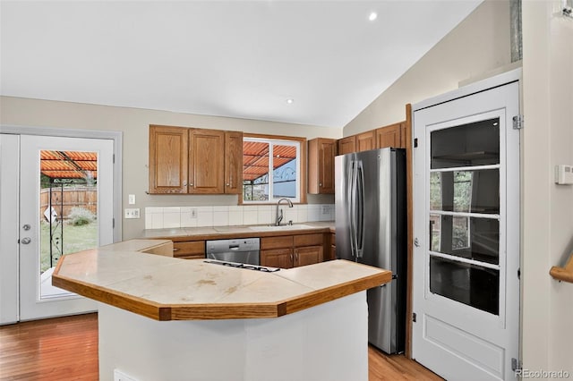 18445 W 59th Dr, Golden, CO 80403 - kitchen featuring appliances with stainless steel finishes, vaulted ceiling, brown cabinets, light wood-type flooring, and recessed lighting
