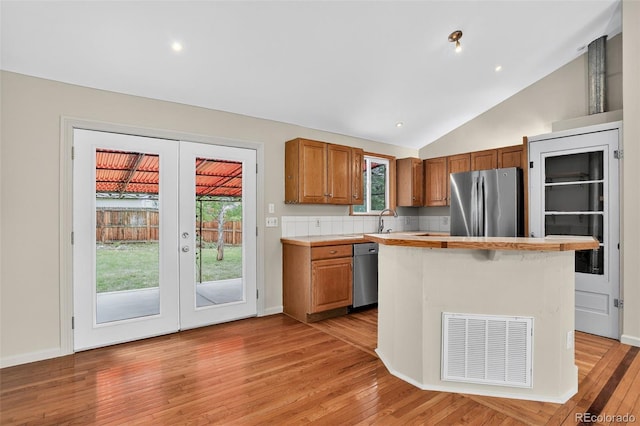 18445 W 59th Dr, Golden, CO 80403 - kitchen featuring appliances with stainless steel finishes, french doors, light countertops, light wood-style flooring, and vaulted ceiling