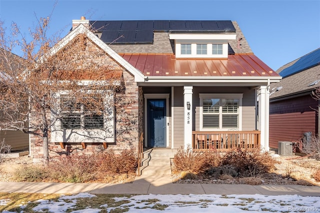 view of front of home with solar panels, covered porch, and central AC