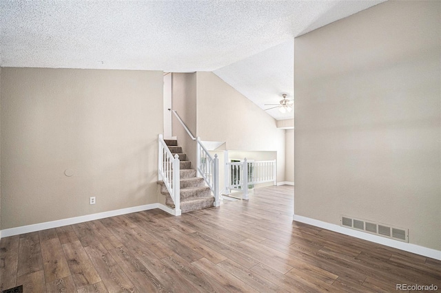 19876 E Brunswick Dr, Aurora, CO 80013 - unfurnished living room with a ceiling fan, stairs, wood finished floors, vaulted ceiling, and a textured ceiling