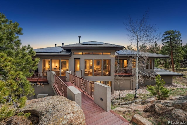 back of house at dusk featuring roof mounted solar panels