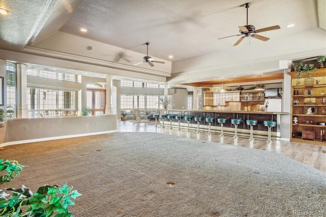 unfurnished living room with crown molding, a textured ceiling, a raised ceiling, ceiling fan, and hardwood / wood-style floors