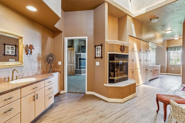 bathroom with hardwood / wood-style flooring, vanity, a tiled fireplace, and a textured ceiling