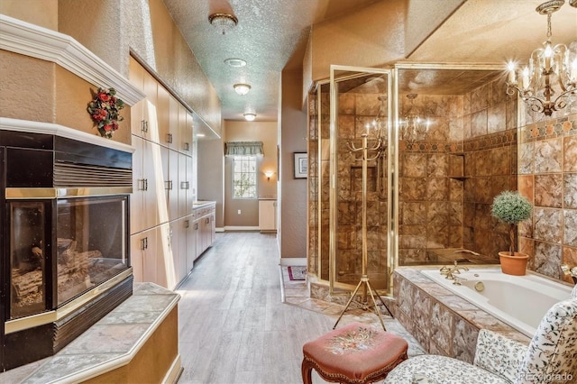 bathroom featuring hardwood / wood-style flooring, plus walk in shower, a chandelier, and a textured ceiling