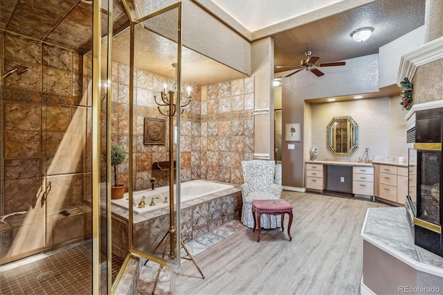 bathroom featuring shower with separate bathtub, a textured ceiling, vanity, hardwood / wood-style floors, and ceiling fan with notable chandelier