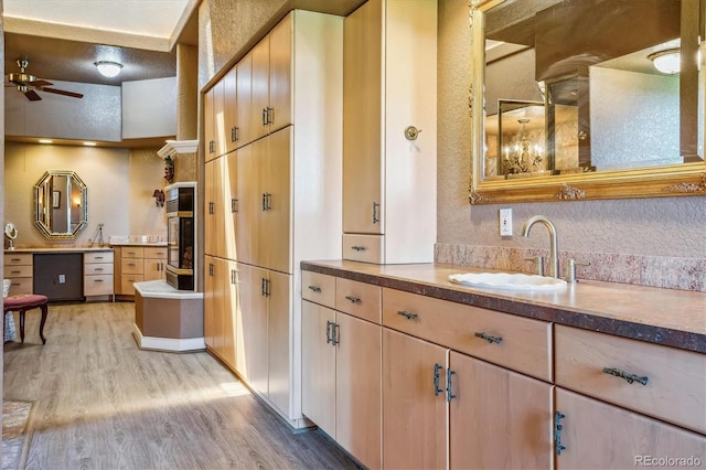 kitchen with ceiling fan, oven, sink, and light hardwood / wood-style flooring