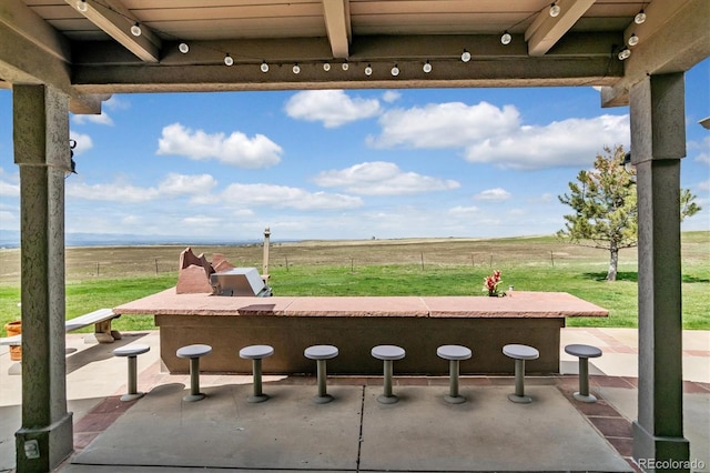 view of patio featuring exterior kitchen and a rural view