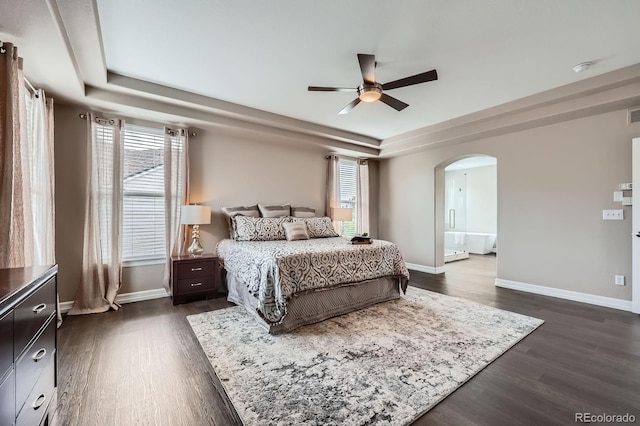 8469 Winter Berry Dr, Castle Pines, CO 80108 - bedroom featuring a raised ceiling, arched walkways, dark wood finished floors, and multiple windows