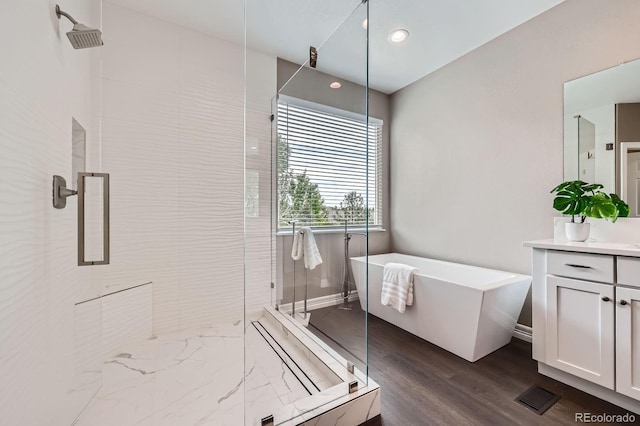 8469 Winter Berry Dr, Castle Pines, CO 80108 - full bath with vanity, a stall shower, a freestanding bath, wood finished floors, and recessed lighting