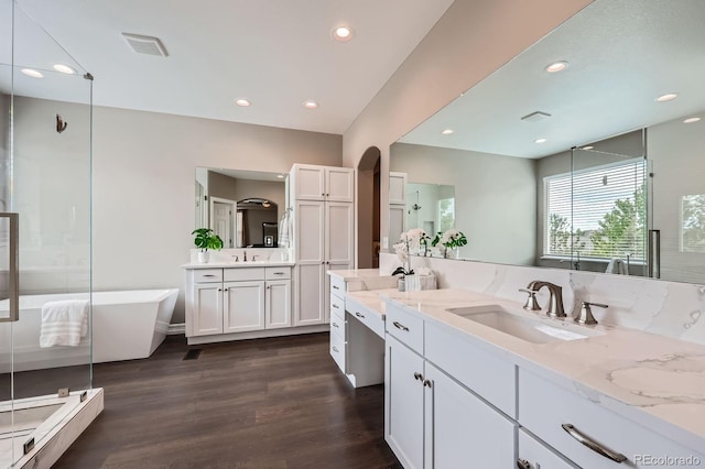 8469 Winter Berry Dr, Castle Pines, CO 80108 - bathroom featuring two vanities, wood finished floors, a soaking tub, recessed lighting, and a shower stall