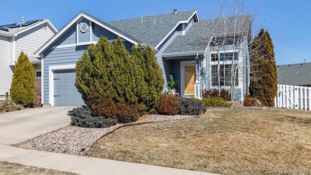 view of front of house featuring concrete driveway, an attached garage, fence, and a shingled roof