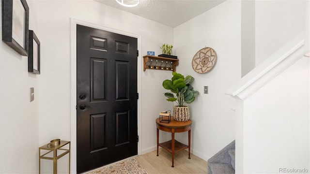 entrance foyer with baseboards, light wood-style floors, and a textured ceiling