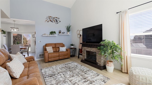 living room featuring visible vents, baseboards, vaulted ceiling, a fireplace, and wood finished floors