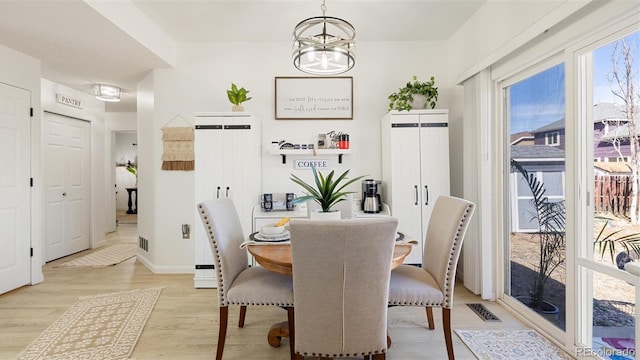 dining area with a notable chandelier, baseboards, light wood-type flooring, and visible vents