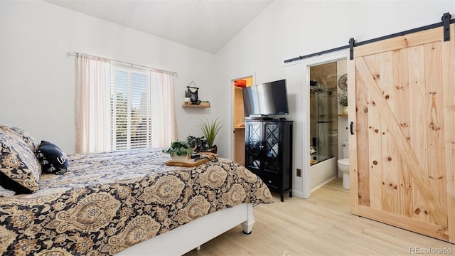 bedroom featuring high vaulted ceiling, a barn door, and wood finished floors