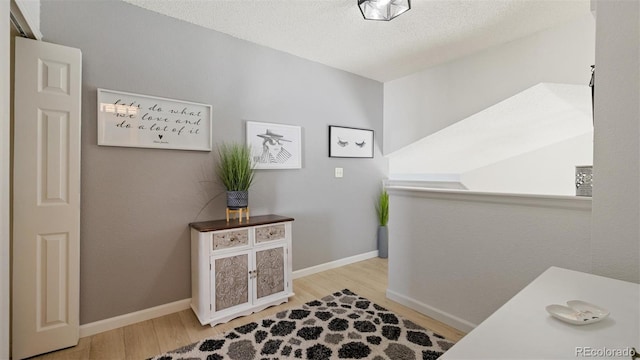 interior space with wood finished floors, baseboards, and a textured ceiling