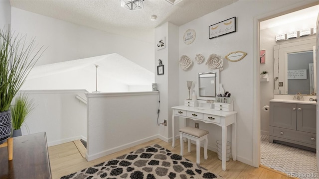 bathroom featuring baseboards, a textured ceiling, wood finished floors, and vanity