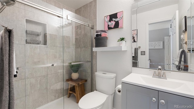 bathroom featuring vanity, a shower stall, and toilet