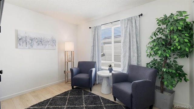 living area with wood finished floors, baseboards, and a textured ceiling