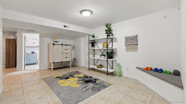 workout room with tile patterned flooring, visible vents, a textured ceiling, and baseboards