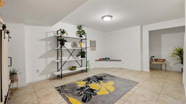 entrance foyer with a barn door, baseboards, a textured ceiling, and tile patterned flooring